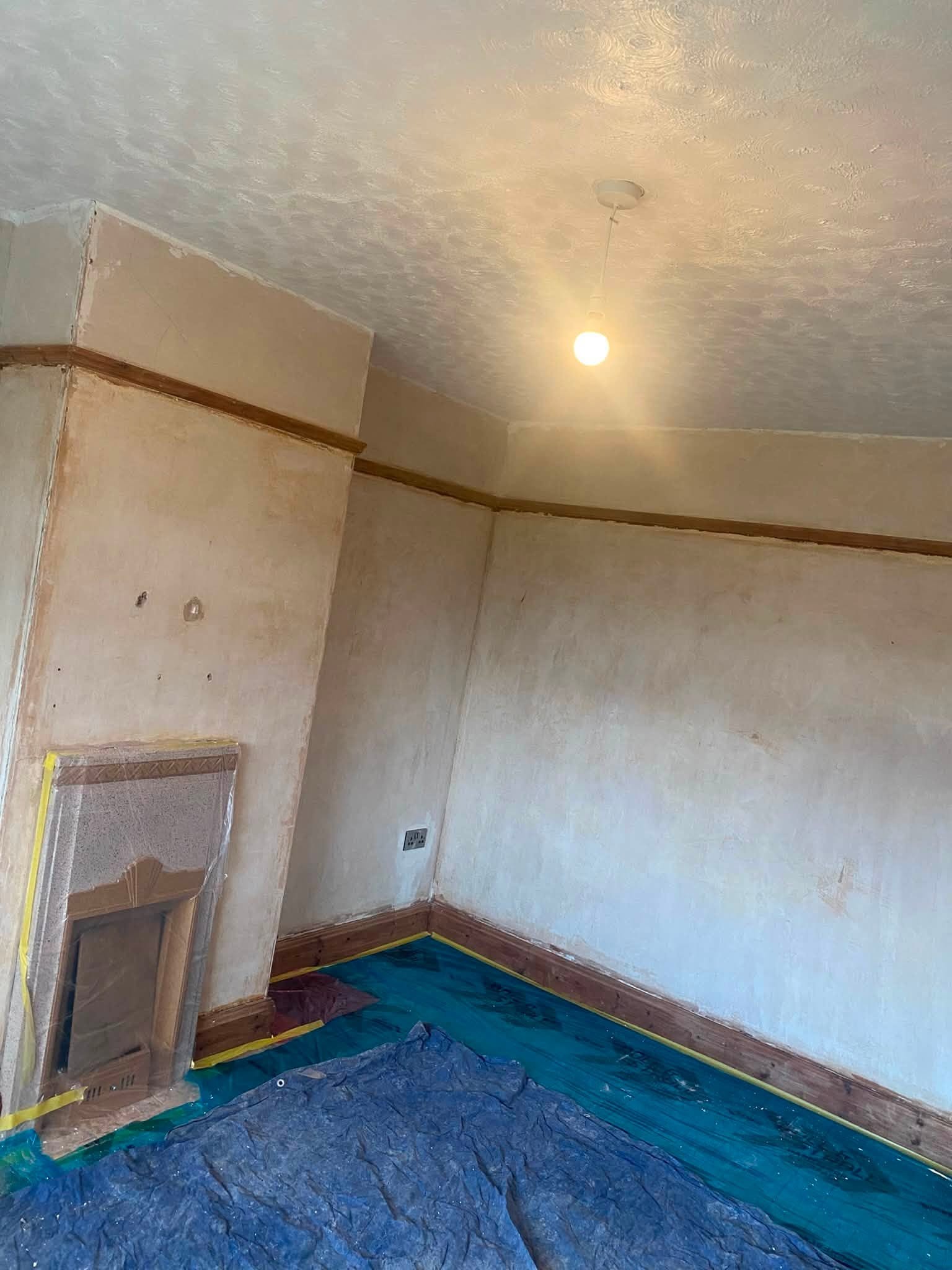 Front room in Oswestry with walls and ceiling plastered and drying, fireplace on the left