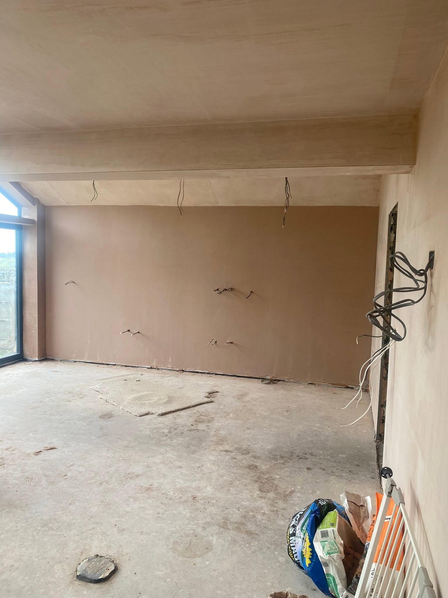 Long wall of the Saint Martins extension in fresh plaster, with the boxed beam above