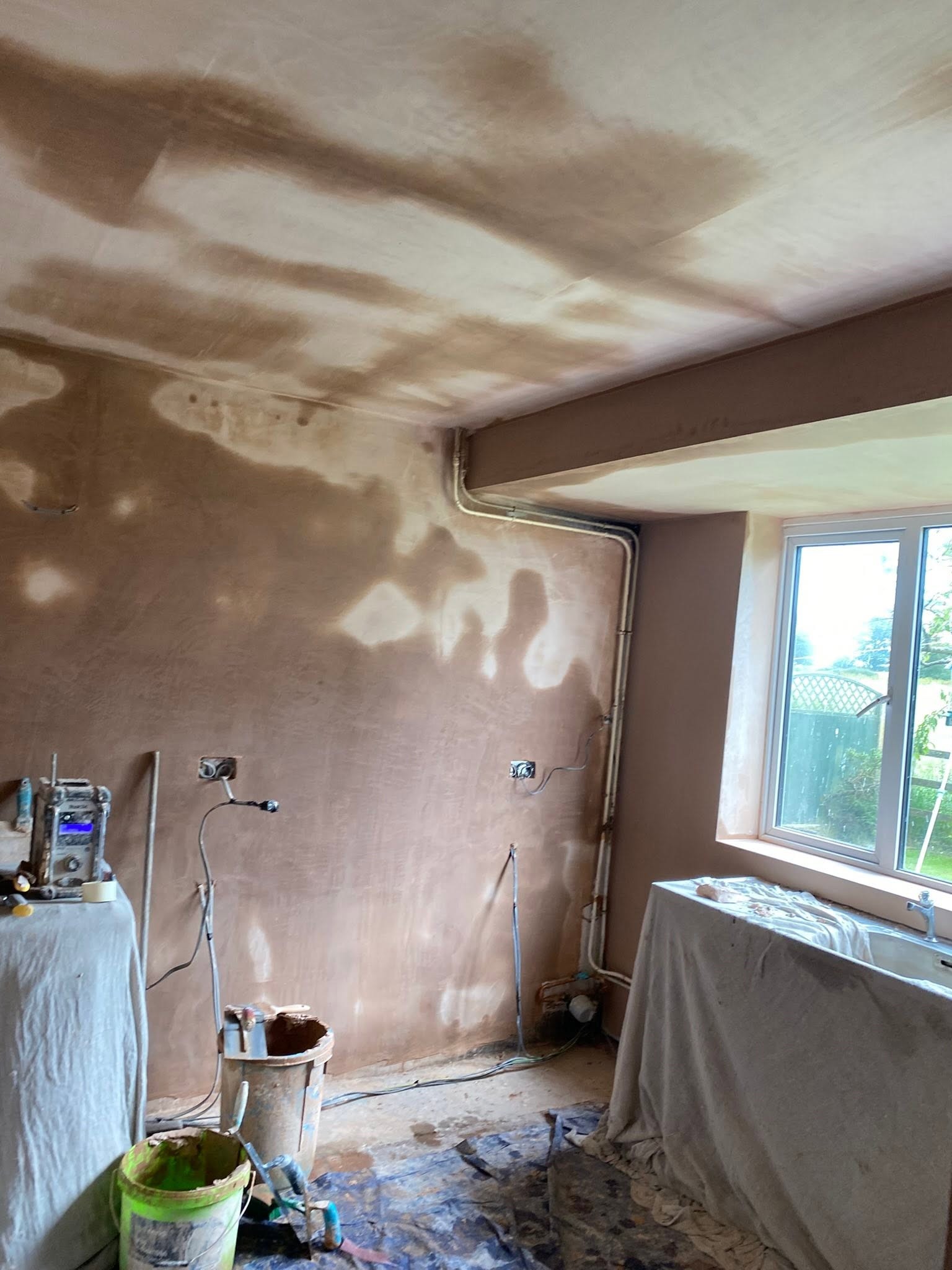 Kitchen wall in Saint Martins freshly plastered round the pipework