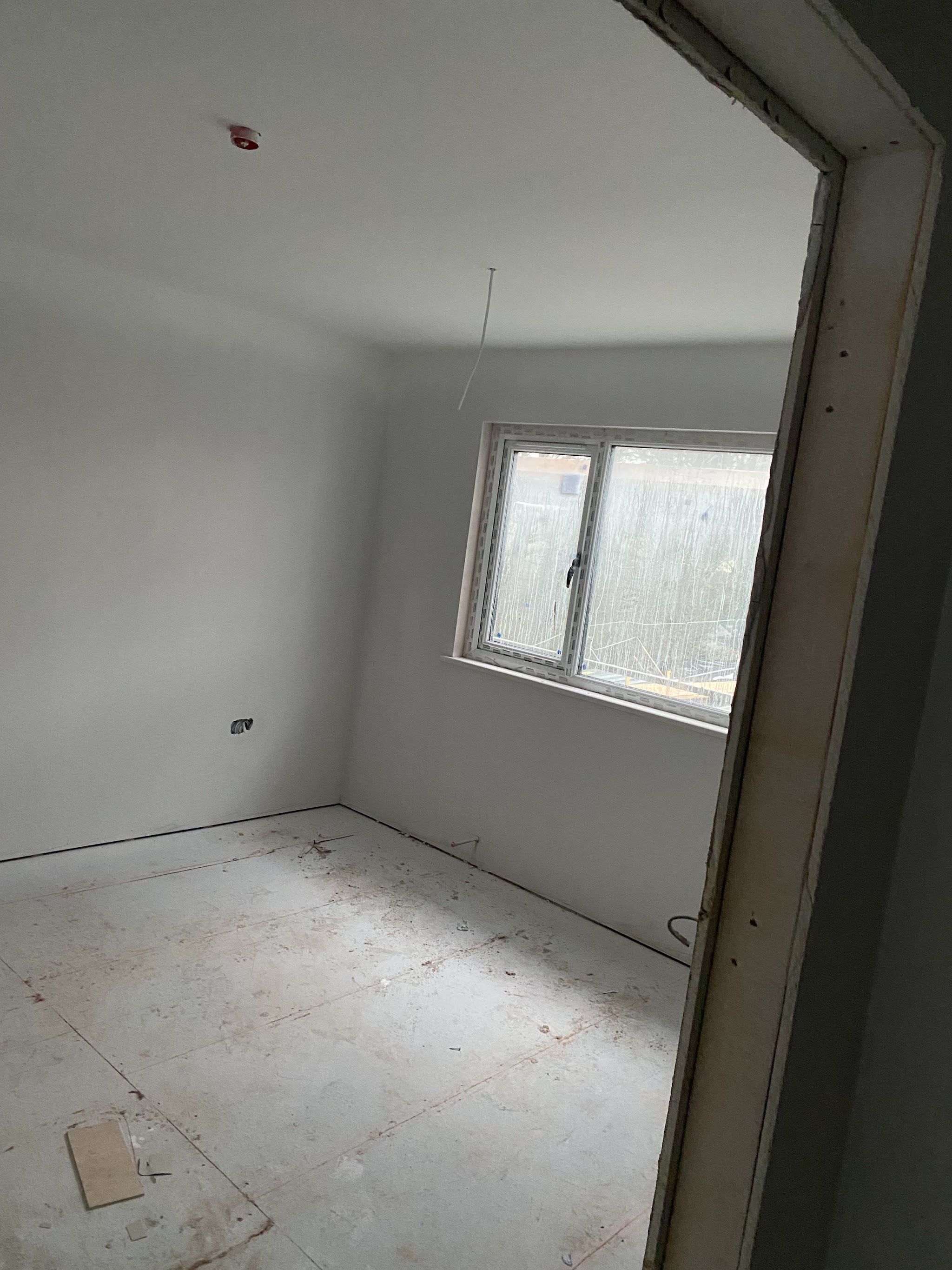 New-build room finished in smooth plaster, seen through the doorway